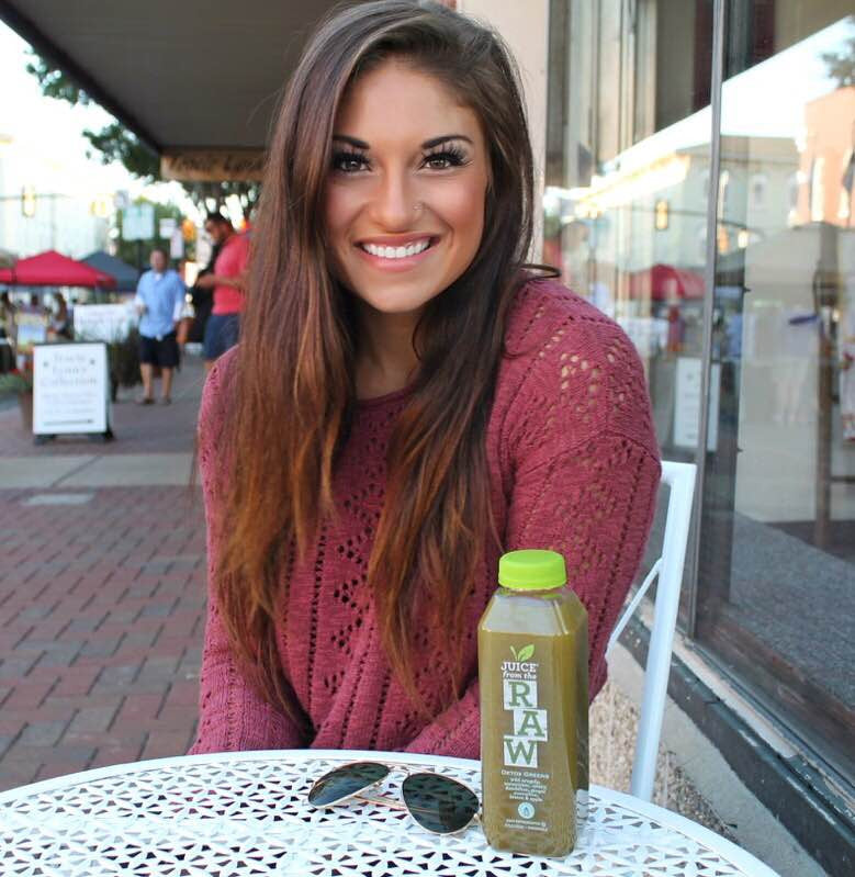 miranda rodriguez sitting at table with juice from the raw bottle