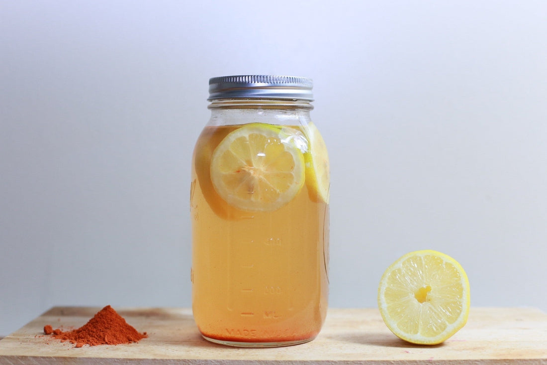 jar with lemonade and a lemon on a beige table